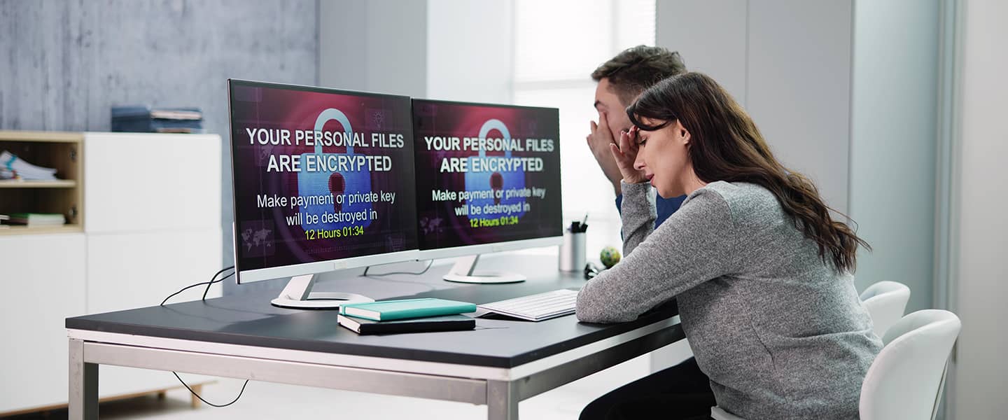 A man and a woman sitting in front of a computer looking stressed with a data breach message on the screen