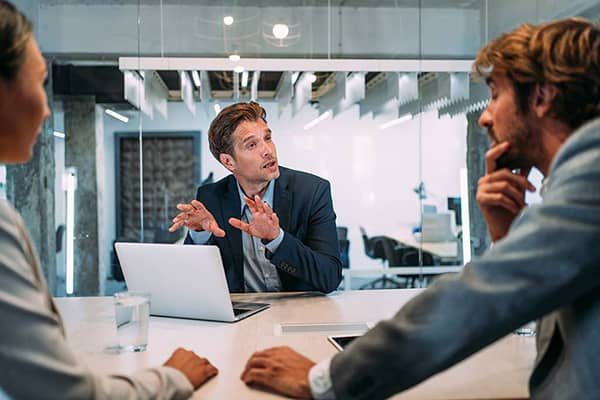 3 businessmen engaged in conversation during a meeting in an office environment